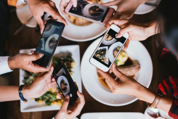 Group of friends going out and taking a photo of Italian food together with mobile phone